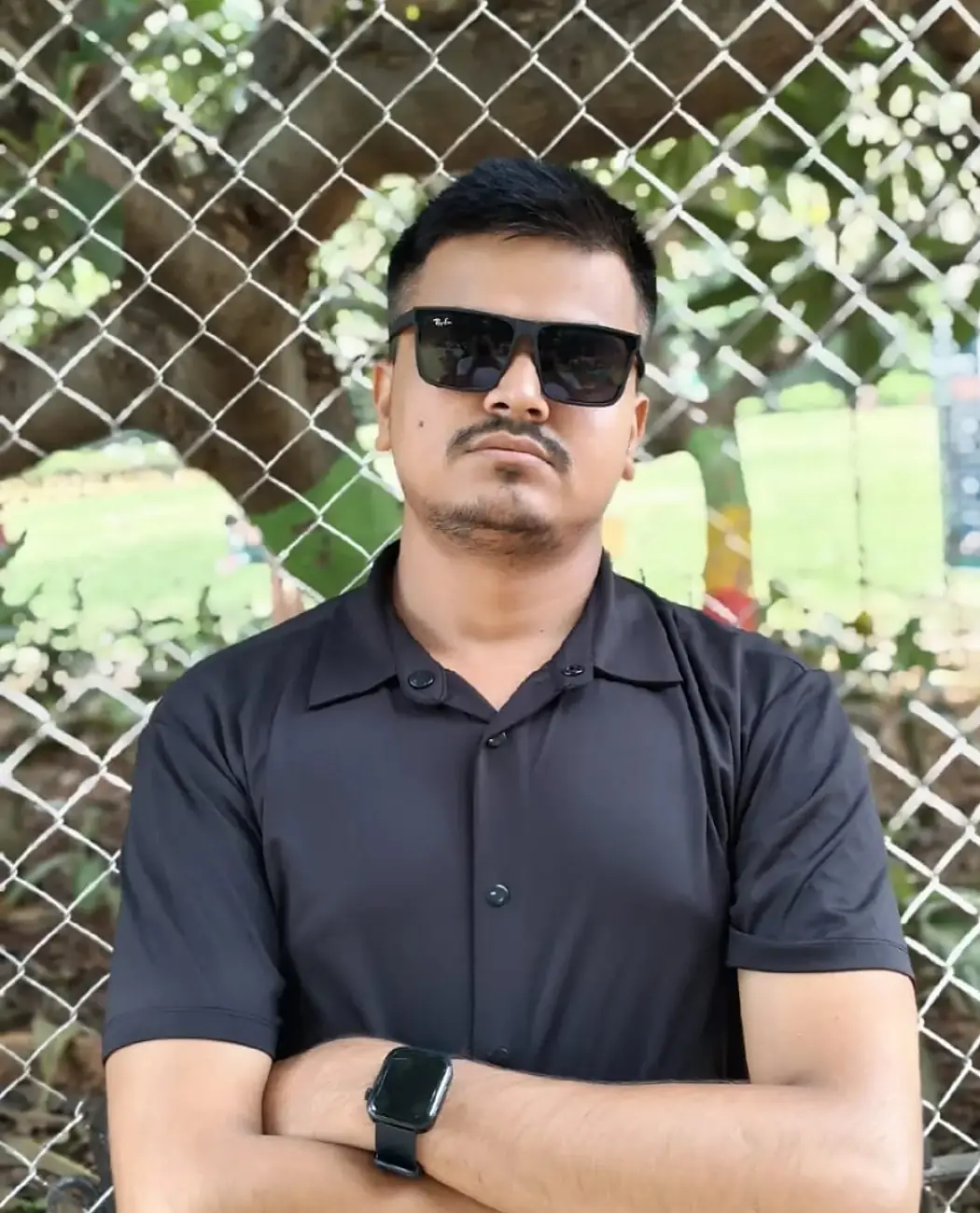 Hemraj in a black shirt and sunglasses, arms folded